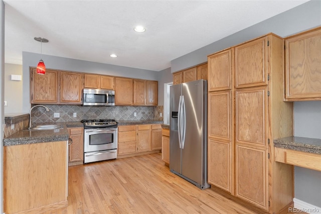 kitchen with stainless steel appliances, sink, light hardwood / wood-style floors, and decorative backsplash