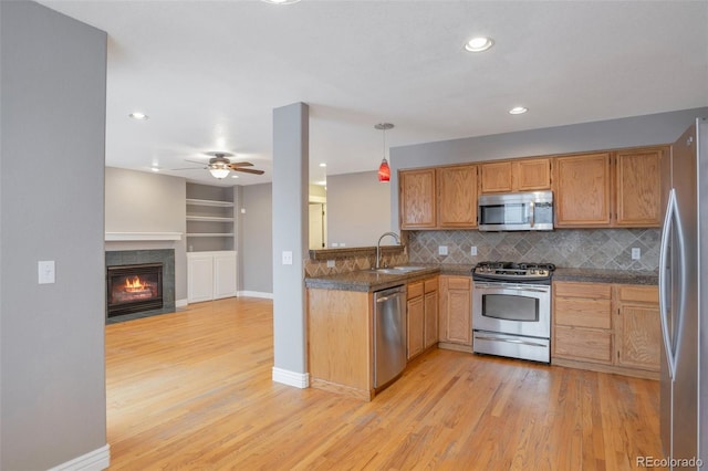 kitchen featuring sink, tasteful backsplash, decorative light fixtures, appliances with stainless steel finishes, and light hardwood / wood-style floors