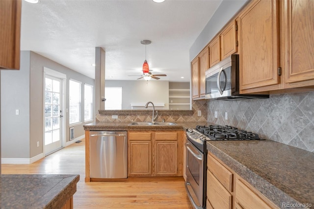 kitchen featuring sink, decorative backsplash, ceiling fan, light hardwood / wood-style floors, and stainless steel appliances