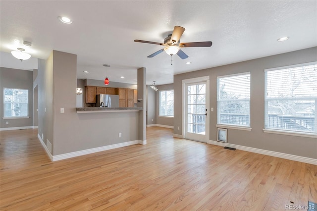 unfurnished living room featuring a textured ceiling, light hardwood / wood-style floors, and ceiling fan