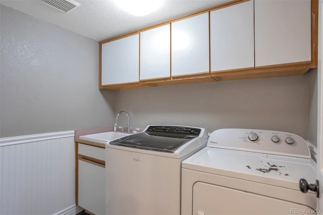 washroom with cabinets, separate washer and dryer, sink, and a textured ceiling