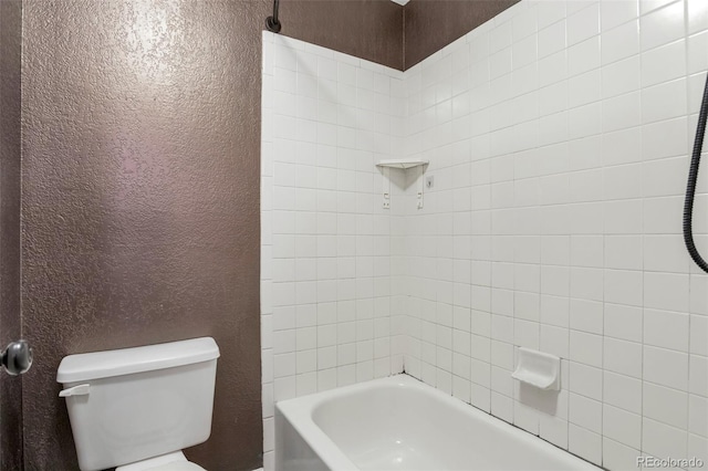 bathroom featuring tiled shower / bath and toilet