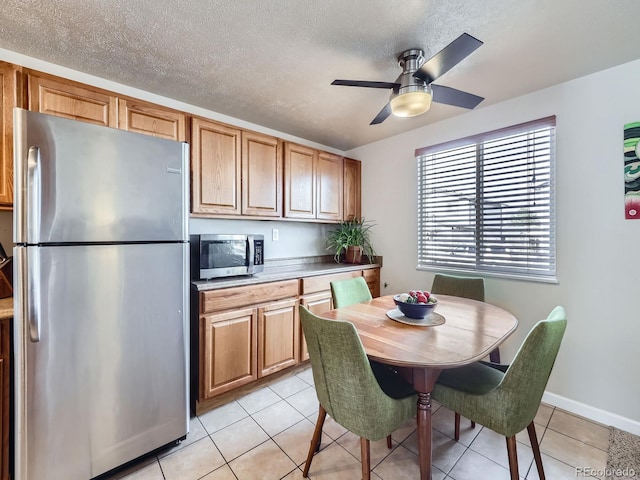 kitchen with ceiling fan, light tile patterned floors, stainless steel appliances, and a textured ceiling