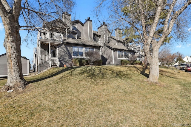 view of front of house with a front yard, a chimney, and a balcony