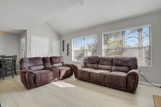 living room featuring lofted ceiling, a textured ceiling, light wood-style flooring, and baseboards