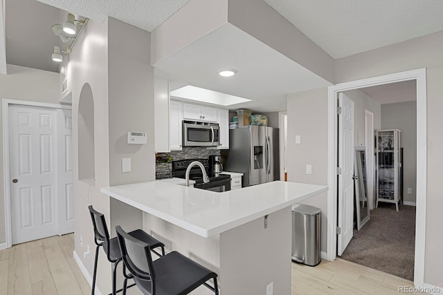 kitchen featuring a skylight, a breakfast bar area, stainless steel appliances, light countertops, and backsplash