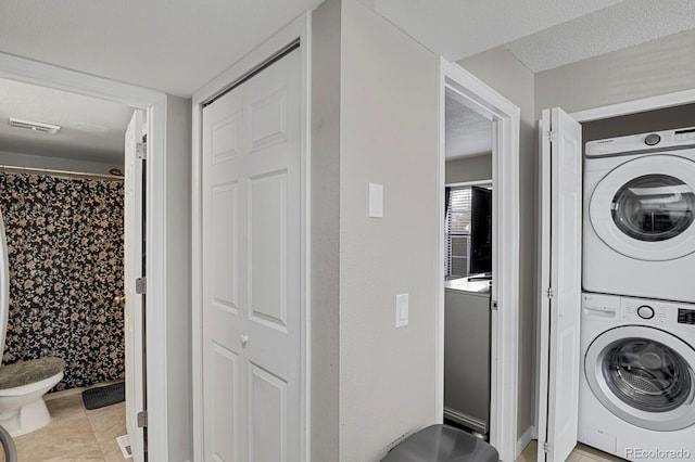 washroom with visible vents, laundry area, a textured ceiling, and stacked washer and clothes dryer