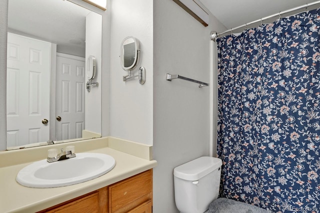 bathroom with curtained shower, vanity, and toilet