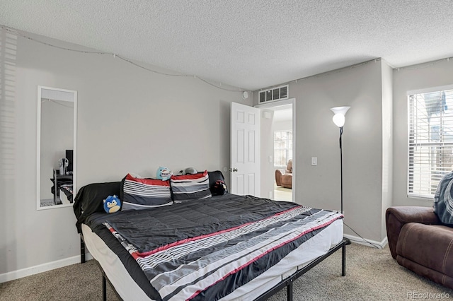 carpeted bedroom featuring visible vents, a textured ceiling, and baseboards