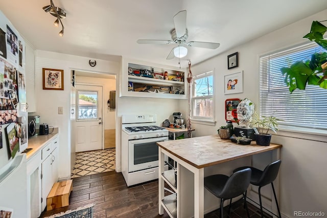 5424 Saulsbury Ct, Arvada, CO 80002 - kitchen featuring gas range gas stove, a ceiling fan, dark wood-style flooring, open shelves, and a kitchen bar