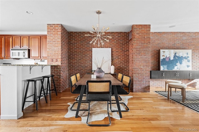 425 S Reed St, Lakewood, CO 80226 - dining room with light wood-type flooring, brick wall, and a chandelier