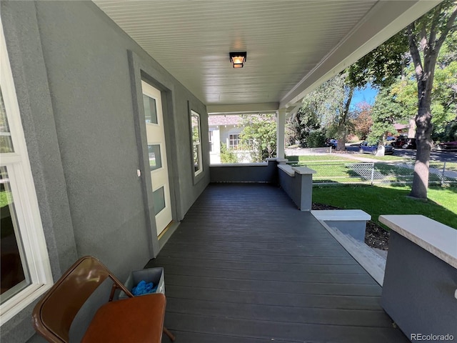 wooden deck featuring a porch and a yard