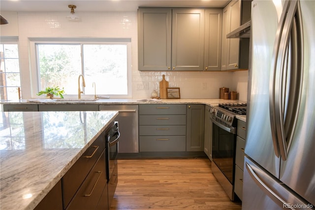 7600 S Ulster Ct, Centennial, CO 80112 - kitchen featuring appliances with stainless steel finishes, a sink, gray cabinets, under cabinet range hood, and light stone countertops
