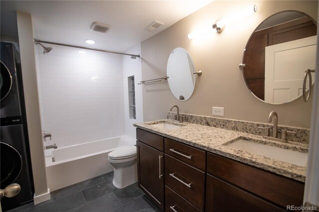 7600 S Ulster Ct, Centennial, CO 80112 - full bath featuring stacked washer / drying machine, toilet, bathing tub / shower combination, double vanity, and tile patterned flooring