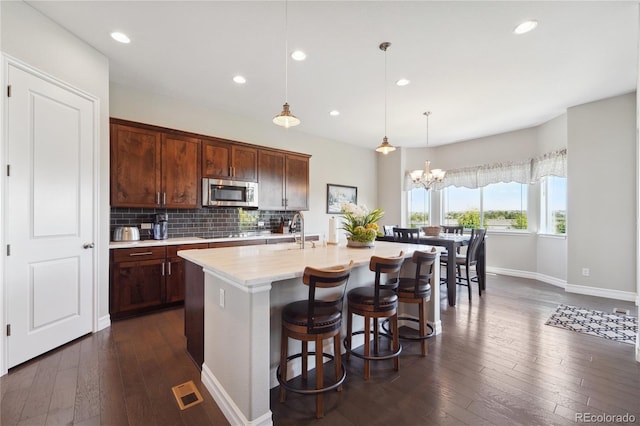 kitchen featuring sink, decorative light fixtures, a center island with sink, a notable chandelier, and decorative backsplash