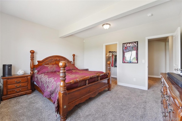 bedroom featuring light colored carpet, a spacious closet, beam ceiling, and a closet