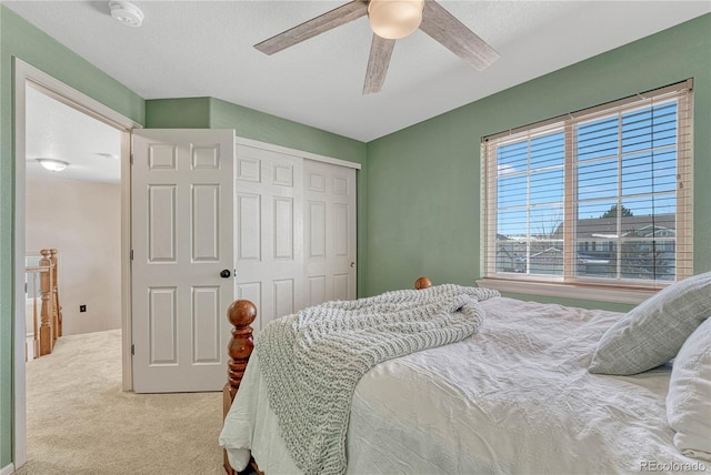 carpeted bedroom with ceiling fan and a closet