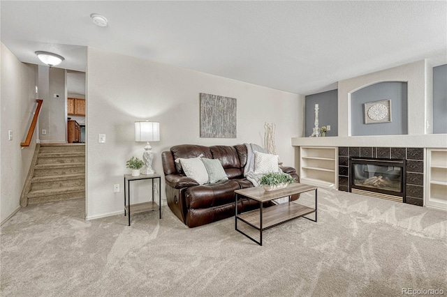 living room featuring a tiled fireplace, carpet floors, and built in features