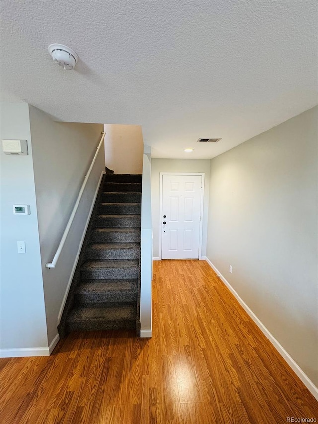 stairway with hardwood / wood-style flooring and a textured ceiling