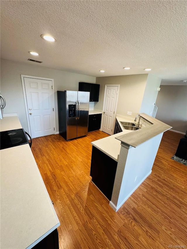 kitchen with wood-type flooring, sink, stainless steel fridge with ice dispenser, and a textured ceiling