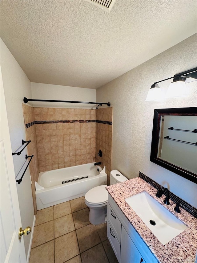 full bathroom featuring tile patterned flooring, tiled shower / bath, toilet, and a textured ceiling