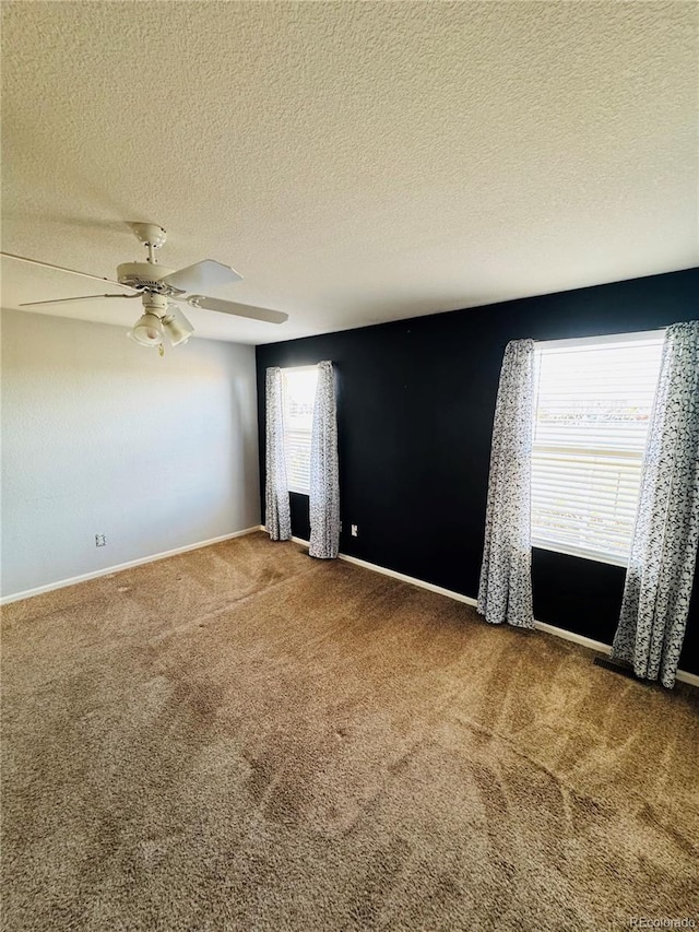 carpeted empty room with ceiling fan, a wealth of natural light, and a textured ceiling