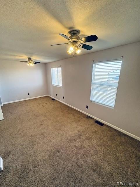 unfurnished room with ceiling fan, a textured ceiling, and dark colored carpet