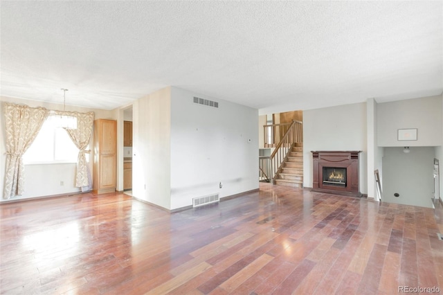 unfurnished living room featuring hardwood / wood-style floors and a textured ceiling