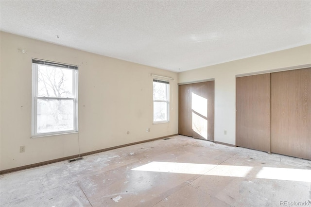 unfurnished bedroom featuring two closets and a textured ceiling