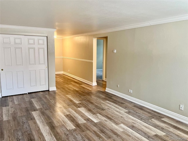 interior space featuring crown molding, baseboards, wood finished floors, and a closet