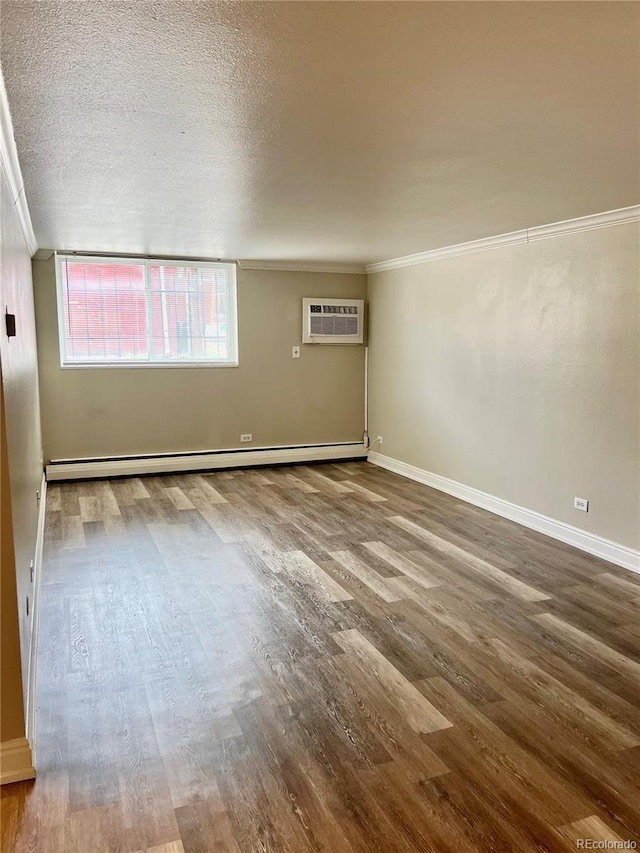 unfurnished room with crown molding, a baseboard radiator, a wall unit AC, and wood finished floors