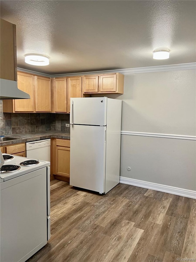 kitchen featuring white appliances, dark countertops, range hood, and dark wood-type flooring