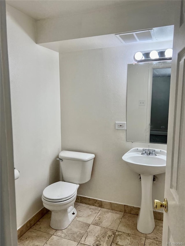 half bath featuring baseboards, visible vents, and toilet