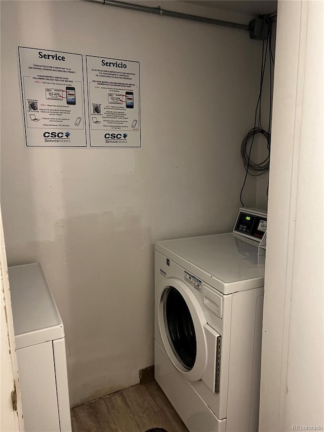 clothes washing area featuring light wood finished floors and washer and clothes dryer