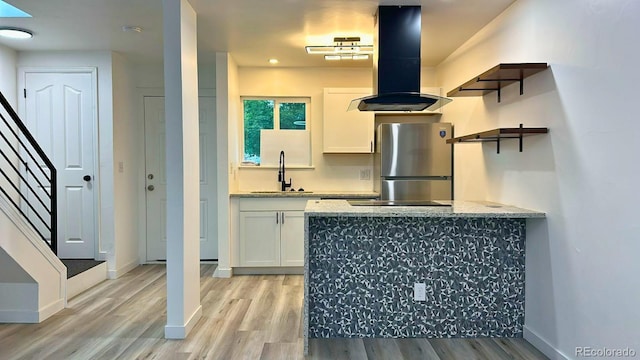 2218 Coronado Pkwy N Unit B, Denver, CO 80229 - kitchen featuring freestanding refrigerator, island range hood, open shelves, light wood-style floors, and white cabinetry