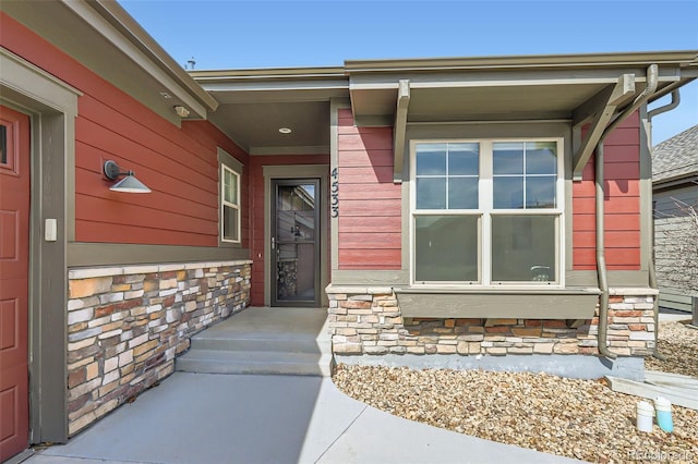 entrance to property with a porch and stone siding