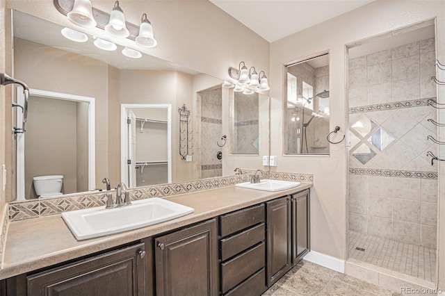 5521 Ensenada St, Denver, CO 80249 - full bathroom featuring toilet, tiled shower, double vanity, a walk in closet, and tile patterned floors
