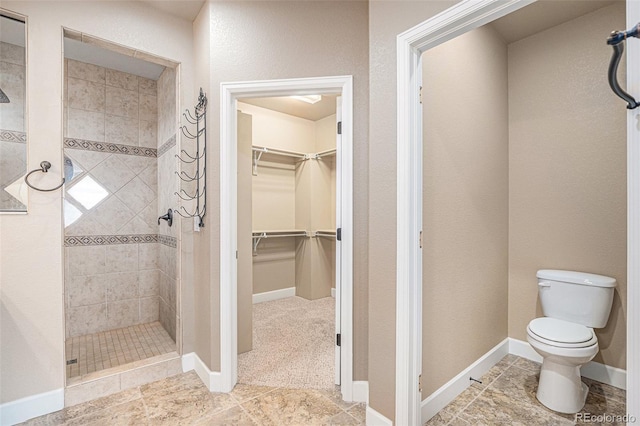 5521 Ensenada St, Denver, CO 80249 - full bath with a stall shower, toilet, a spacious closet, baseboards, and tile patterned floors