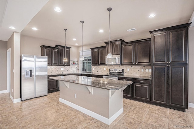 5521 Ensenada St, Denver, CO 80249 - kitchen featuring appliances with stainless steel finishes, a center island, backsplash, a kitchen bar, and light stone countertops