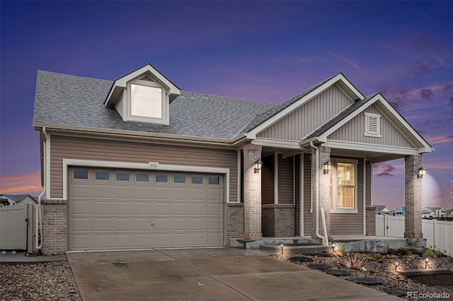 5521 Ensenada St, Denver, CO 80249 - view of front of property with a porch, concrete driveway, brick siding, a shingled roof, and an attached garage