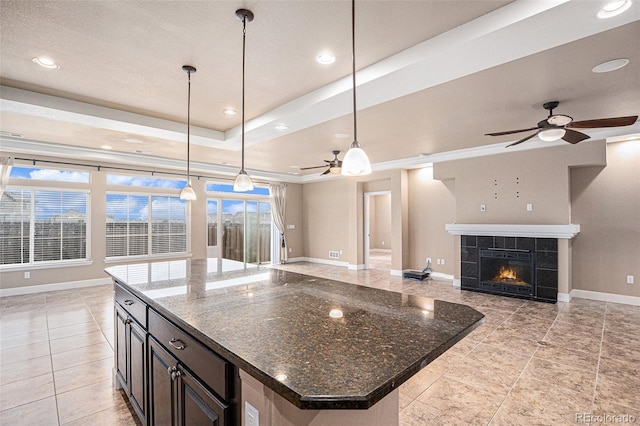 5521 Ensenada St, Denver, CO 80249 - kitchen with a ceiling fan, open floor plan, baseboards, light tile patterned floors, and a tile fireplace