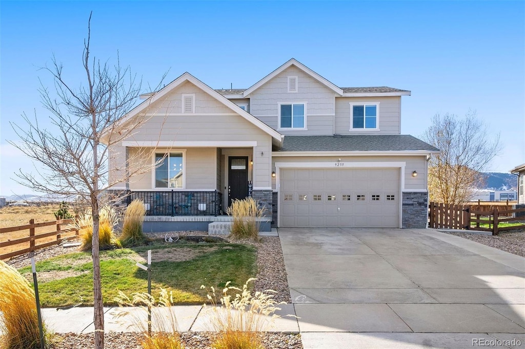 view of front of home with covered porch, a garage, and a front lawn