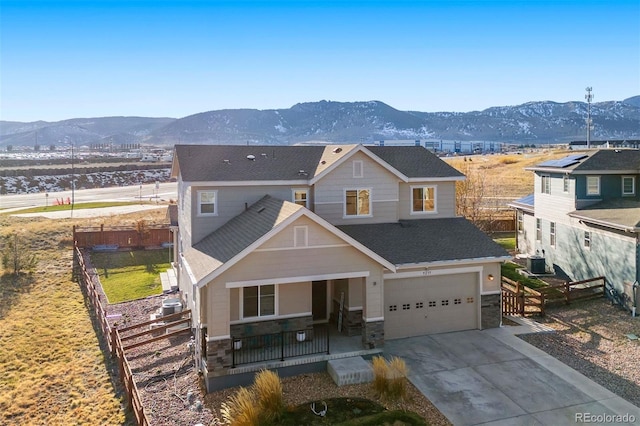 view of front facade featuring a mountain view, a porch, central AC, and a garage