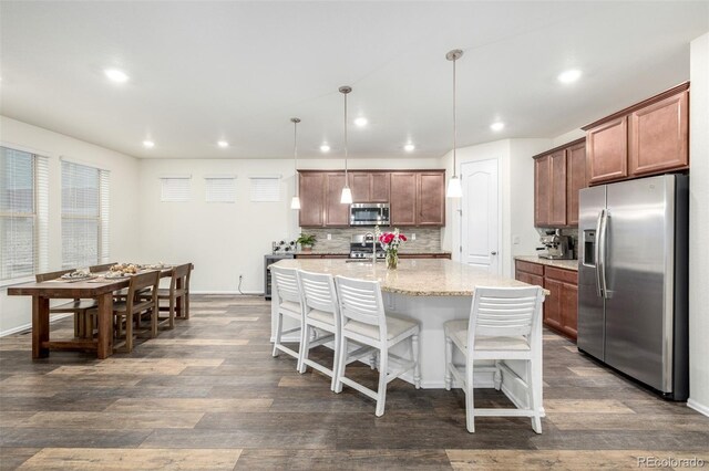 9723 Bennett Peak St, Littleton, CO 80125 - kitchen with appliances with stainless steel finishes, recessed lighting, dark wood-style floors, decorative backsplash, and a breakfast bar area