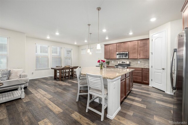 9723 Bennett Peak St, Littleton, CO 80125 - kitchen featuring stainless steel appliances, dark wood-style floors, tasteful backsplash, a kitchen island, and recessed lighting