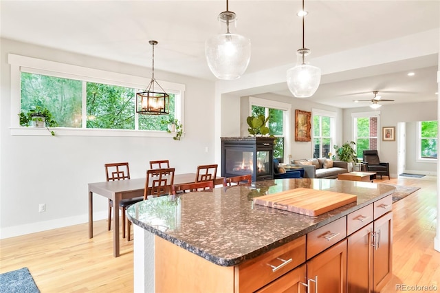 4414 Wolff St, Denver, CO 80212 - kitchen featuring light wood finished floors, dark stone countertops, decorative light fixtures, a chandelier, and a multi sided fireplace