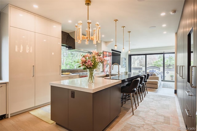 kitchen featuring decorative light fixtures, modern cabinets, a large island with sink, a sink, and open floor plan