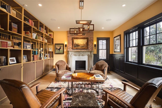 sitting room with a fireplace, wainscoting, a wealth of natural light, and light wood-style floors