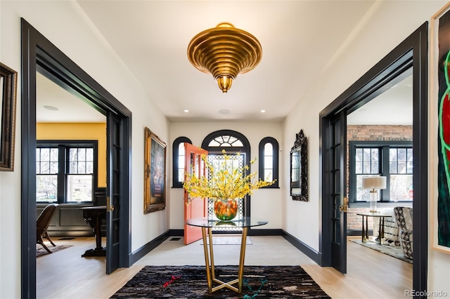 entryway with light wood-style floors, baseboards, and plenty of natural light