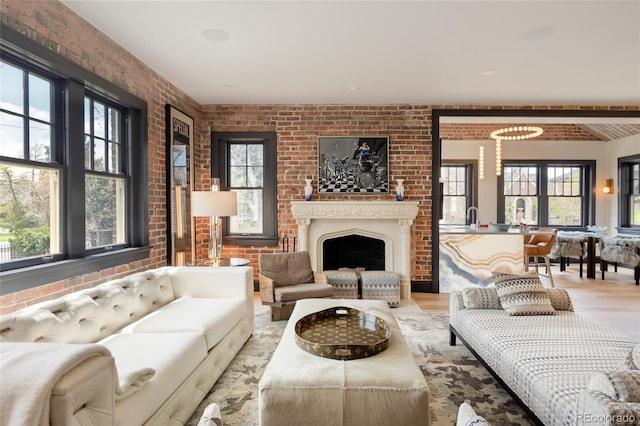 living area with brick wall, wood finished floors, and a fireplace